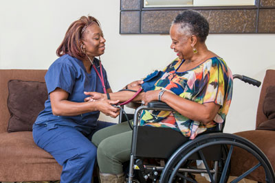 Woman in wheelchair and nurse taking her blood pressure.